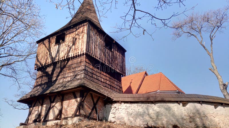 Stará drevená zvonica pri opevnenom kostole.
