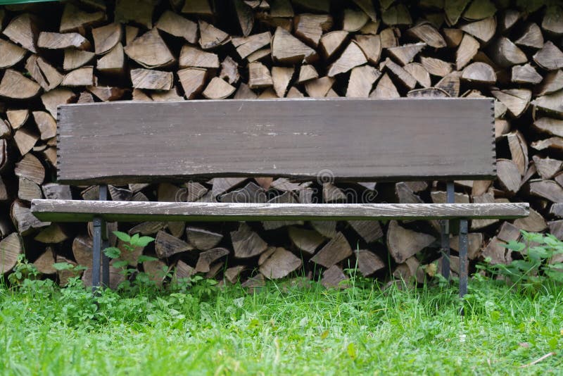 Old wooden bench on a background of a stack of logs royalty free stock photo