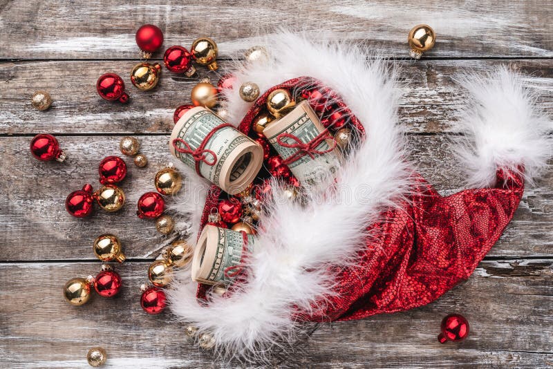 Old wooden Christmas background, Santa Claus hat full of baubles and money. Top view