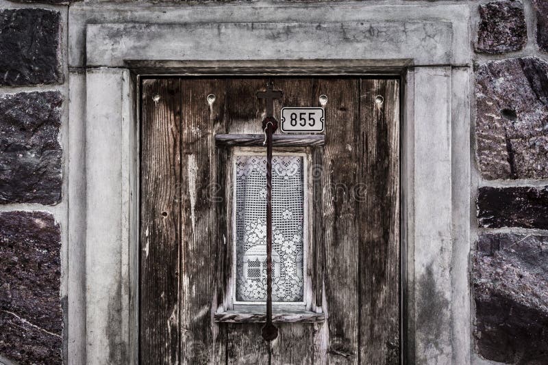 Vintage image with a wooden door and its small window, from an old wall stoned alpine house. Picture taken in the Switzerland mountains. Vintage image with a wooden door and its small window, from an old wall stoned alpine house. Picture taken in the Switzerland mountains.