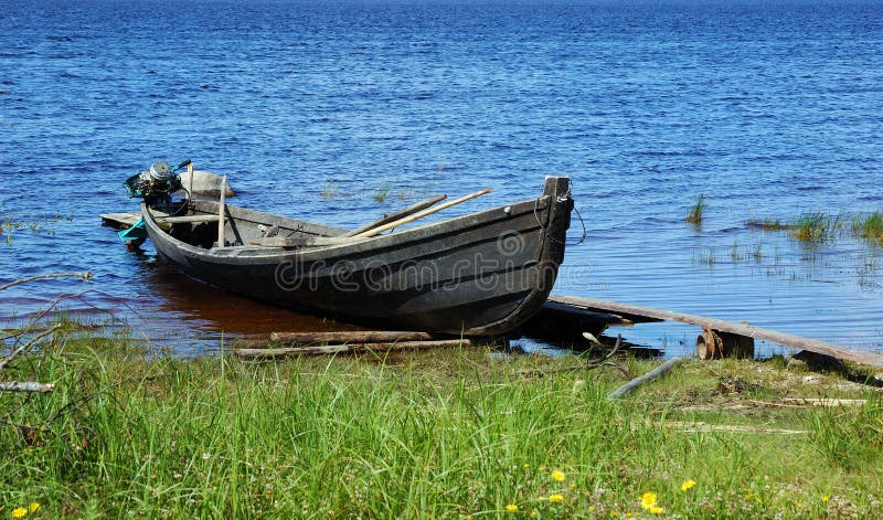 Old wooden fishing motor boat by the lake bank