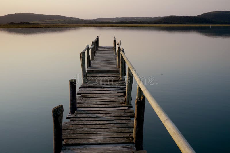 Old wooden jetty leading into a calm river