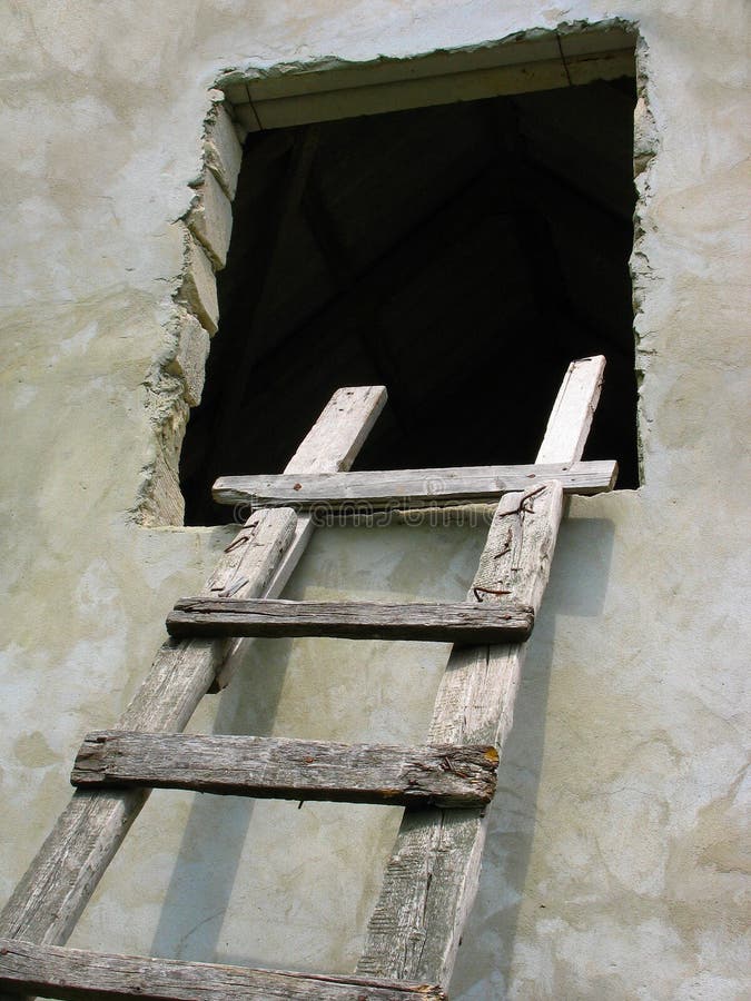 Old wooden ladder to window over the wall