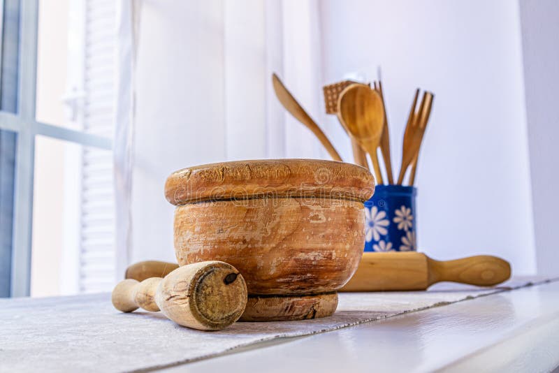 old wooden mortar with pestle inside on white table with grey tablecloth