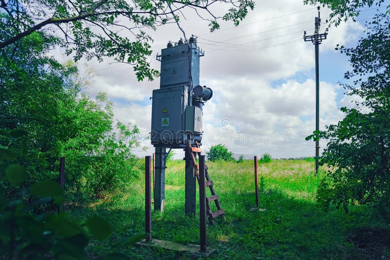 Old working rural electrical distribution transformer in the forest. Sunny day, the concept of industrial.