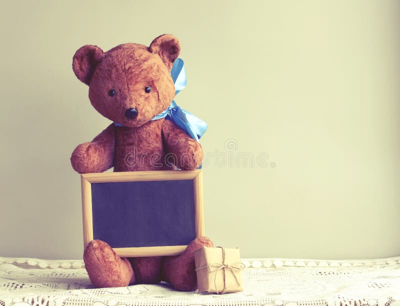 Old worn toy bear with blue bow, photo frame, gift box stock photo Old worn toy bear with blue bow, photo frame, gift box stock photo