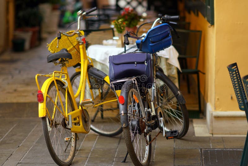 An old yellow bicycle and a modern black electric bicycle parked in a narrow street of Corfu stock photos An old yellow bicycle and a modern black electric bicycle parked in a narrow street of Corfu stock photos