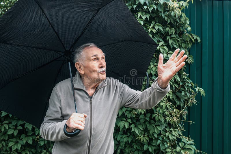 Elderly Man with an Umbrella is Sitting on a Bench. an Old Man with a