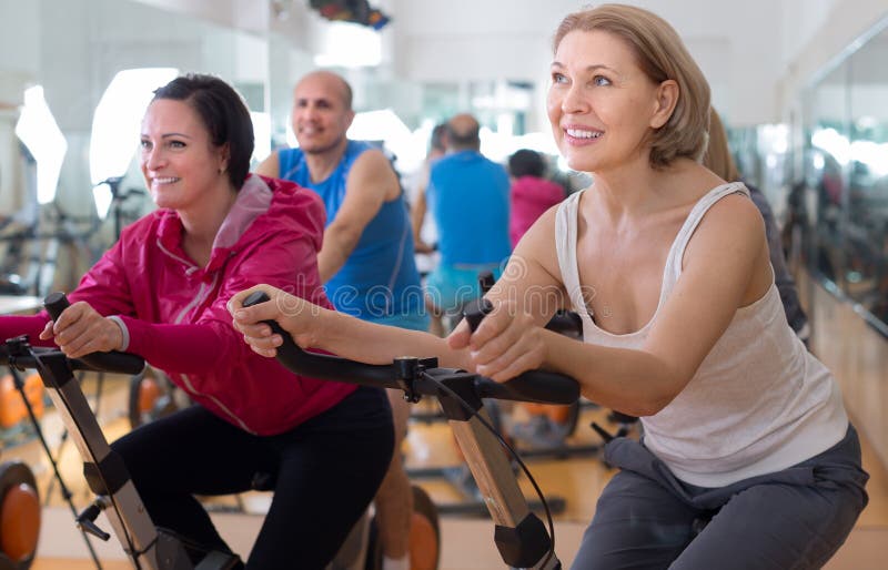 Satisfied older people do sports on exercise bikes