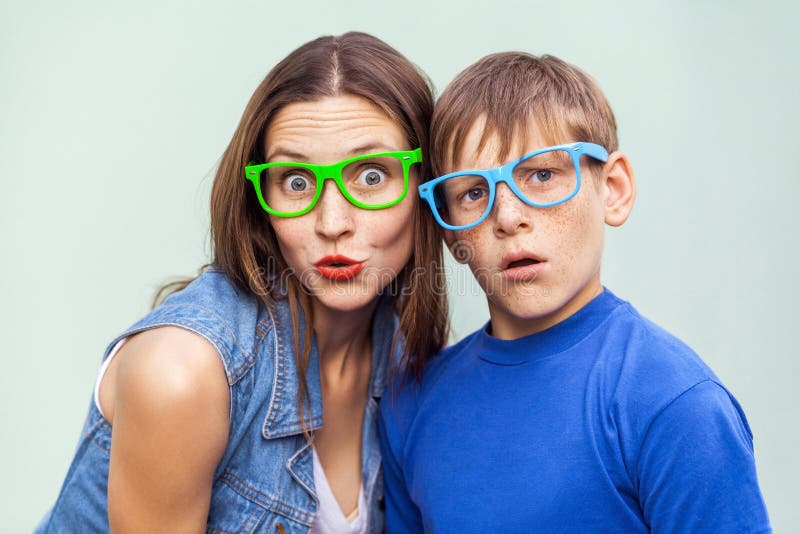 Older sister and her brother with freckles, posing over light blue background together on summer time, looking at camera