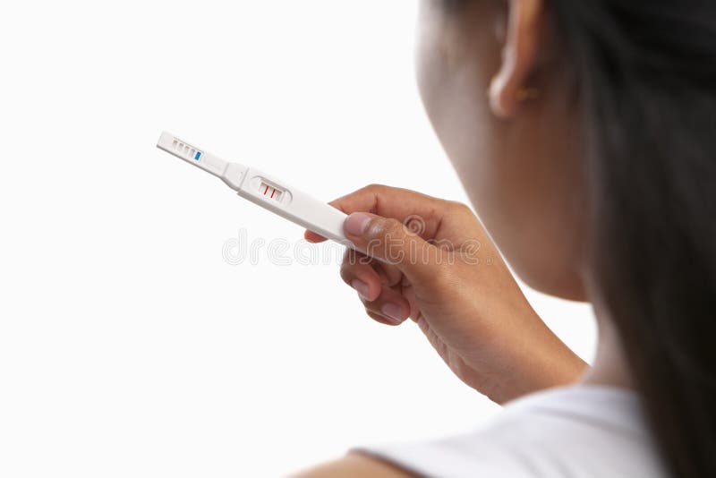 Young woman looking at pregnancy test result, taken from behind. Young woman looking at pregnancy test result, taken from behind