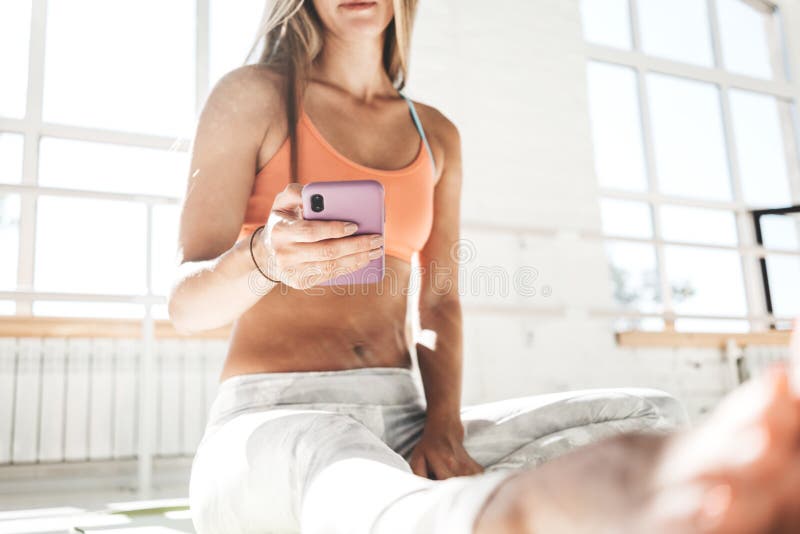Olhares da menina de Tannde no telefone celular e no cargo feito no blogue após a aptidão para malhar fotografia de stock Olhares da menina de Tannde no telefone celular e no cargo feito no blogue após a aptidão para malhar fotografia de stock