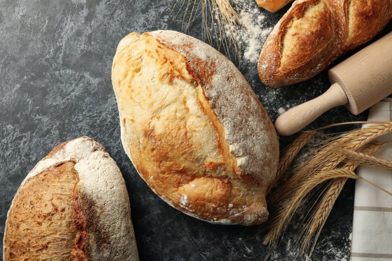 Olika bröd, spindel och rullstift på svart bakgrund av smokey arkivbild