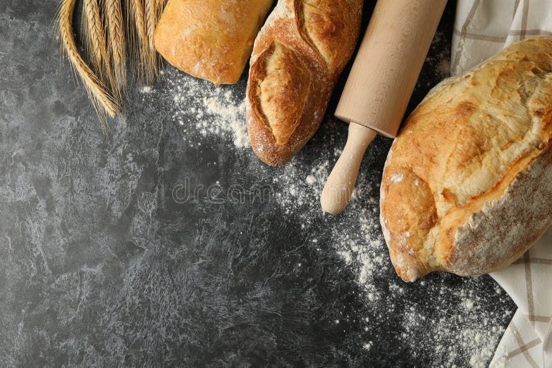 Olika bröd, spindel och rullstift på svart bakgrund av smokey royaltyfri foto