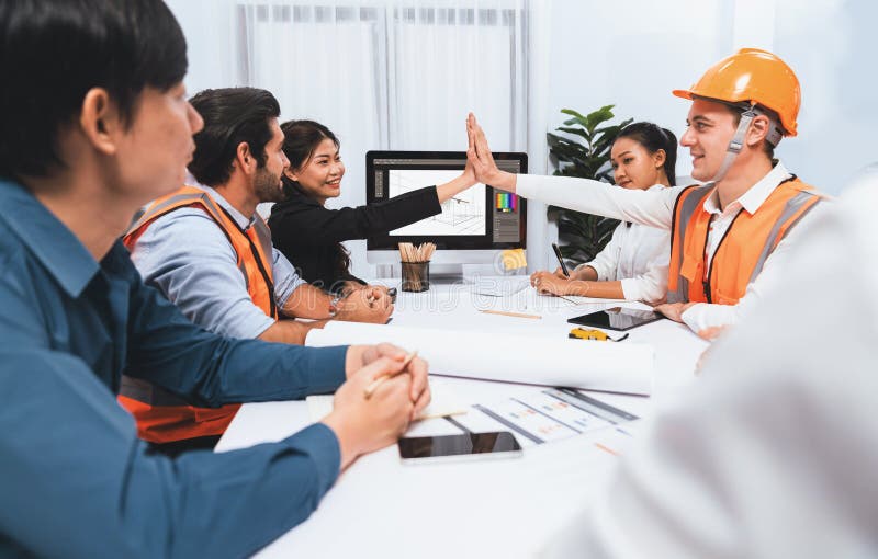 Diverse group of civil engineer and client celebrate and high five after make successful agreement on architectural project, reviewing construction plan and building blueprint at meeting table.Prudent. Diverse group of civil engineer and client celebrate and high five after make successful agreement on architectural project, reviewing construction plan and building blueprint at meeting table.Prudent