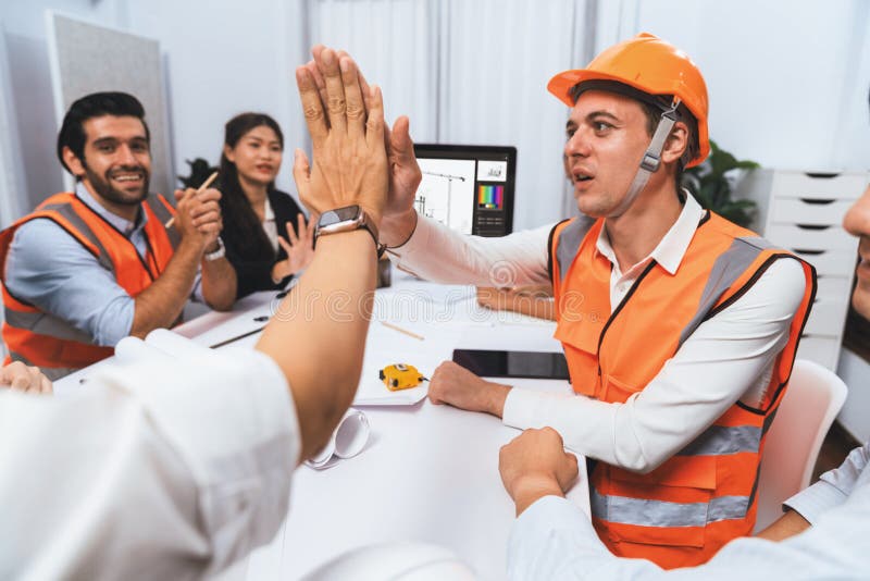 Diverse group of civil engineer and client celebrate and high five after make successful agreement on architectural project, reviewing construction plan and building blueprint at meeting table.Prudent. Diverse group of civil engineer and client celebrate and high five after make successful agreement on architectural project, reviewing construction plan and building blueprint at meeting table.Prudent