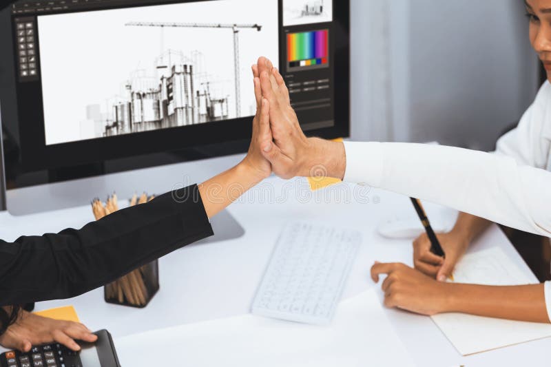 Diverse group of civil engineer and client celebrate and high five after make successful agreement on architectural project, reviewing construction plan and building blueprint at meeting table.Prudent. Diverse group of civil engineer and client celebrate and high five after make successful agreement on architectural project, reviewing construction plan and building blueprint at meeting table.Prudent