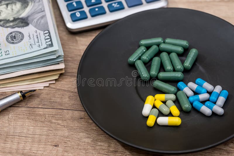olika preventivpillerar på plattan med pennan, räknemaskinen och dollaren arkivfoton olika preventivpillerar på plattan med pennan, räknemaskinen och dollaren arkivfoton