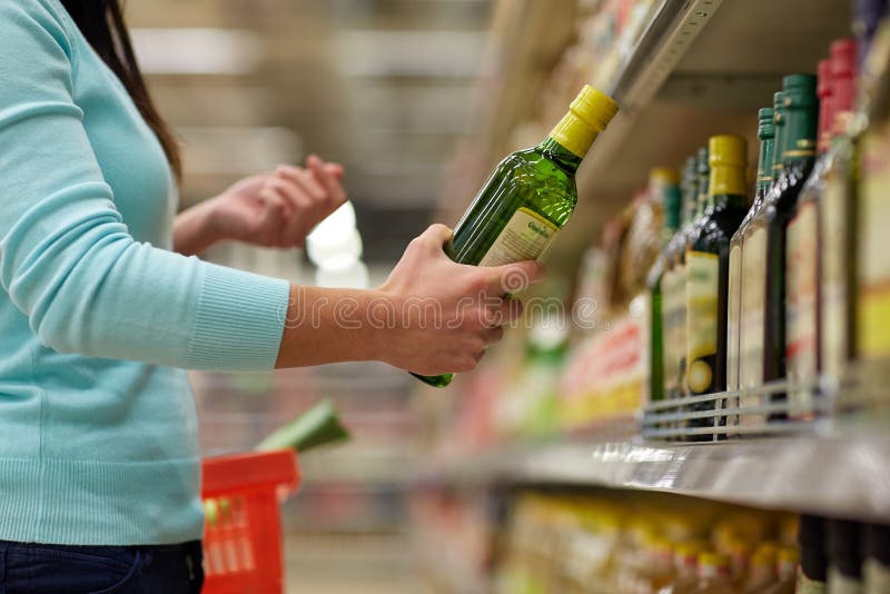Sale, shopping, food, consumerism and people concept - woman buying olive oil at grocery store or supermarket. Sale, shopping, food, consumerism and people concept - woman buying olive oil at grocery store or supermarket