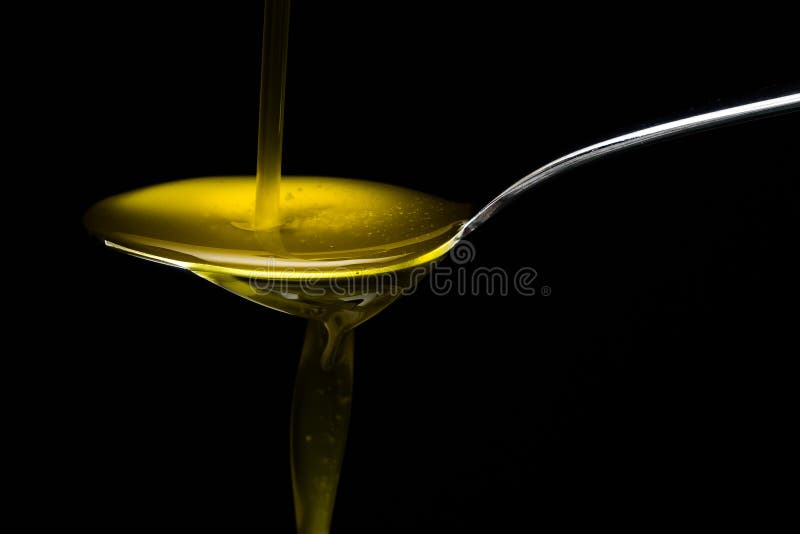Olio d'oliva dorato sopra il cucchiaio del metallo fotografie stock libere da diritti Olio d'oliva dorato sopra il cucchiaio del metallo fotografie stock libere da diritti