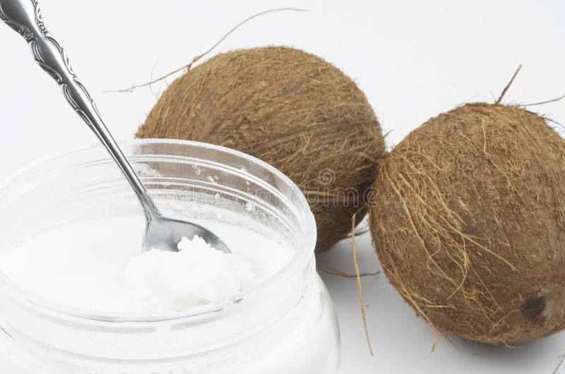 Coconut oil in container pictured with two whole coconuts on a white background. Coconut oil in container pictured with two whole coconuts on a white background.