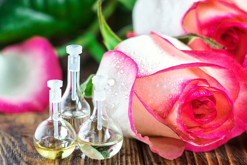 Olio essenziale in bottiglia di vetro con i fiori rosa su fondo di legno Piccole bottiglie di profumo Trattamento di bellezza Con fotografia stock libera da diritti Olio essenziale in bottiglia di vetro con i fiori rosa su fondo di legno Piccole bottiglie di profumo Trattamento di bellezza Con fotografia stock libera da diritti