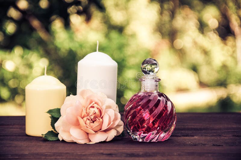 Olio rosa fragrante in una bella bottiglia di vetro Elisir, candele e fiori rosa Concetto della stazione termale Tintura d'annata fotografia stock libera da diritti Olio rosa fragrante in una bella bottiglia di vetro Elisir, candele e fiori rosa Concetto della stazione termale Tintura d'annata fotografia stock libera da diritti