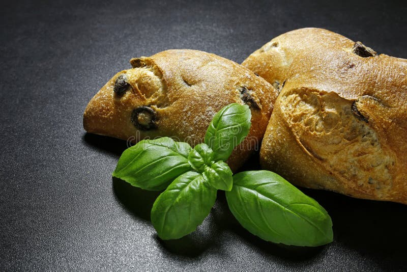 Olive ciabattas with basil leaves on black background