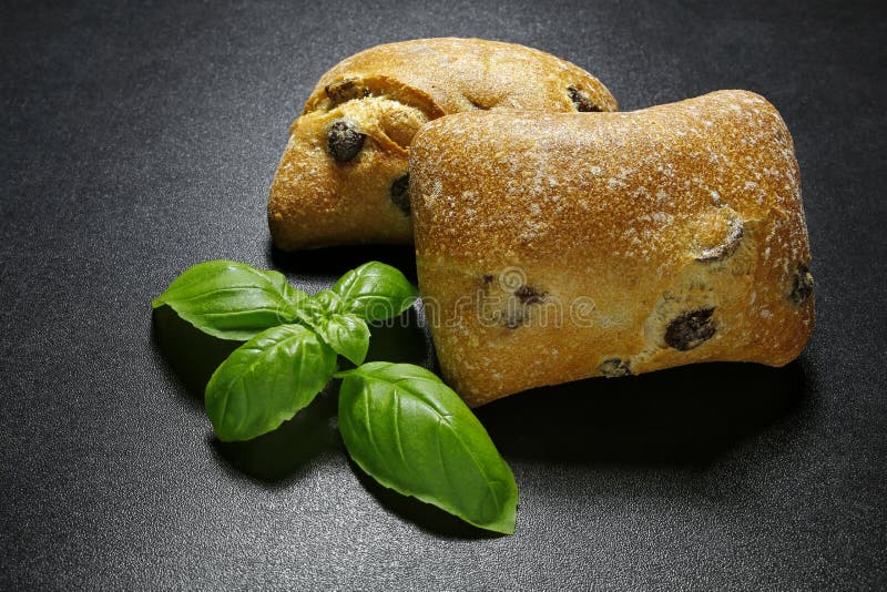 Closeup of olive ciabattas with basil leaves on black background