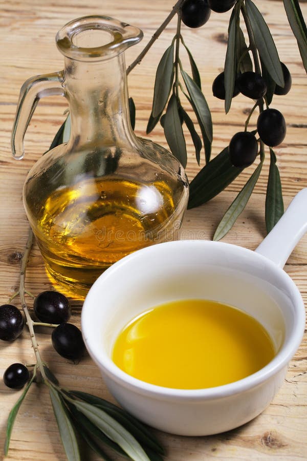 Un'ampolla e una ciotola di olio extra vergine di oliva e un ramo di olive fresche.