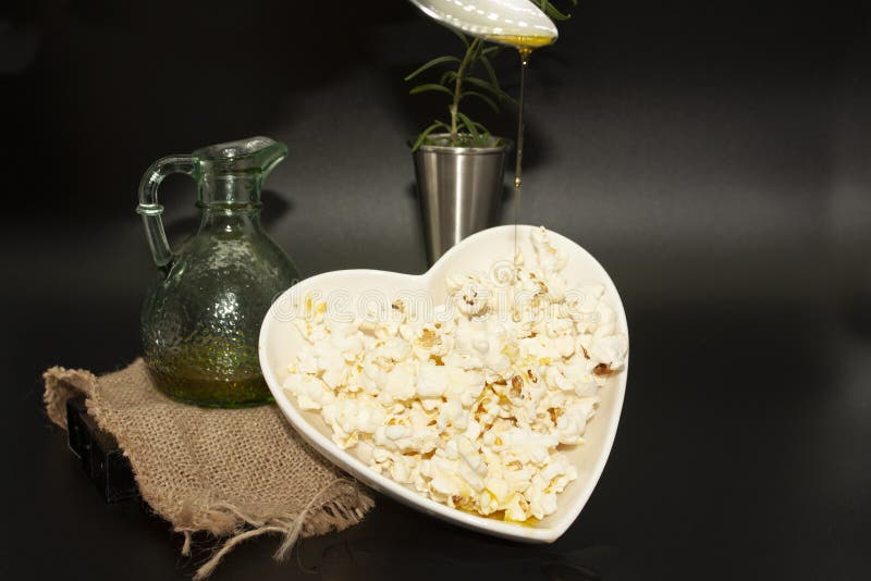 Olive oil and fresh rosemary dressing falling over popped popcorn in a heart-shaped bowl