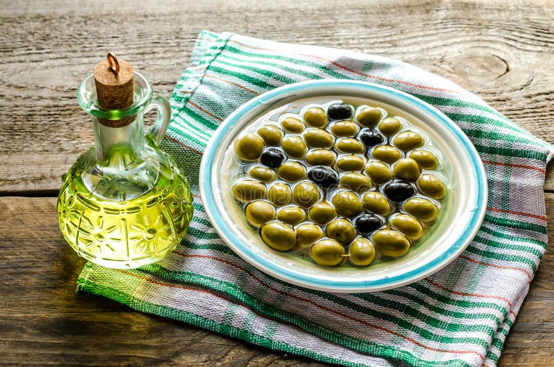 Mixed Olives in a Bowl with Rosemary, Olive Oil and Garlic on a Rustic
