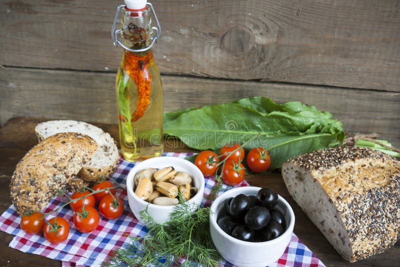 Olives noires et moules dans des cuvettes en céramique, des tomates fraîches, le pain et la bouteille d'huile d'olive avec des ép images stock Olives noires et moules dans des cuvettes en céramique, des tomates fraîches, le pain et la bouteille d'huile d'olive avec des ép images stock