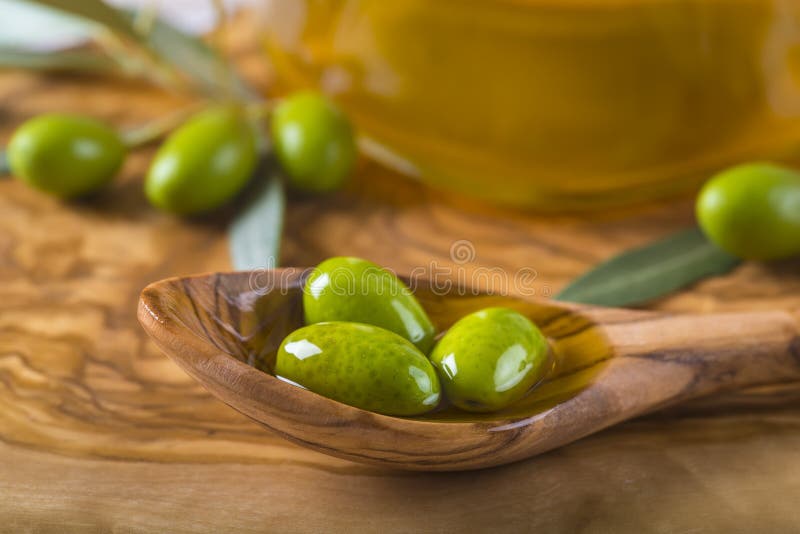 Olives vertes et huile sur une cuillère en bois