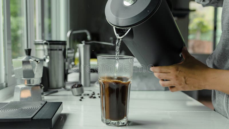 Om care utilizează ceainicul turnând apă caldă, făcând cafea cu gheață sau cafea americană rece în paharul cu unealtă digitală pen royalty free stock images