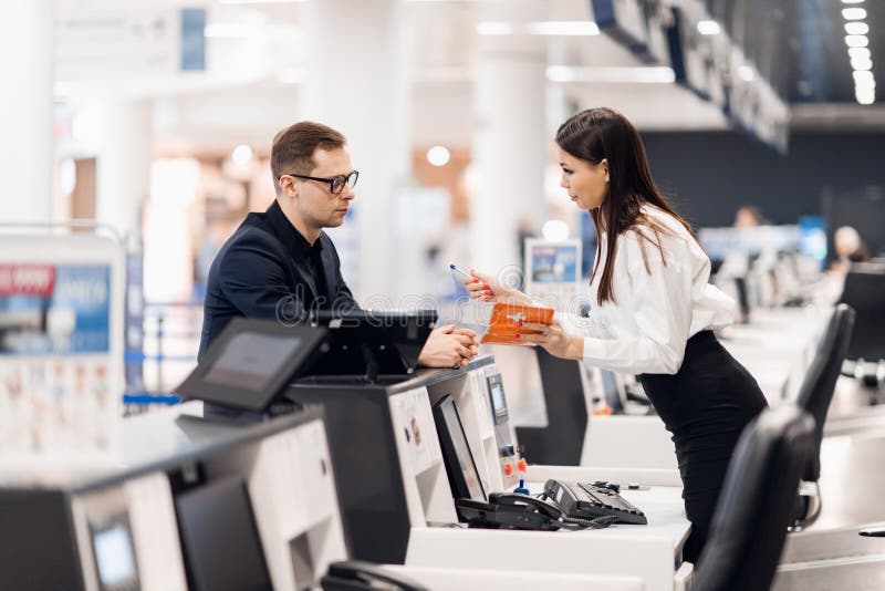 Om de afaceri chipeș care se ocupă de biletele de avion la ghișeul companiei aeriene royalty free stock image