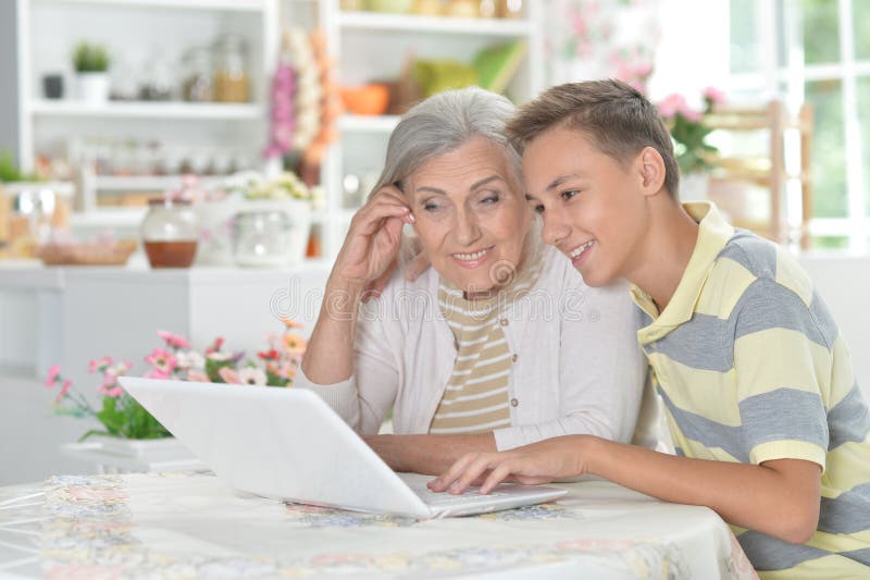 Oma met kleinzoon die thuis een laptop gebruikt