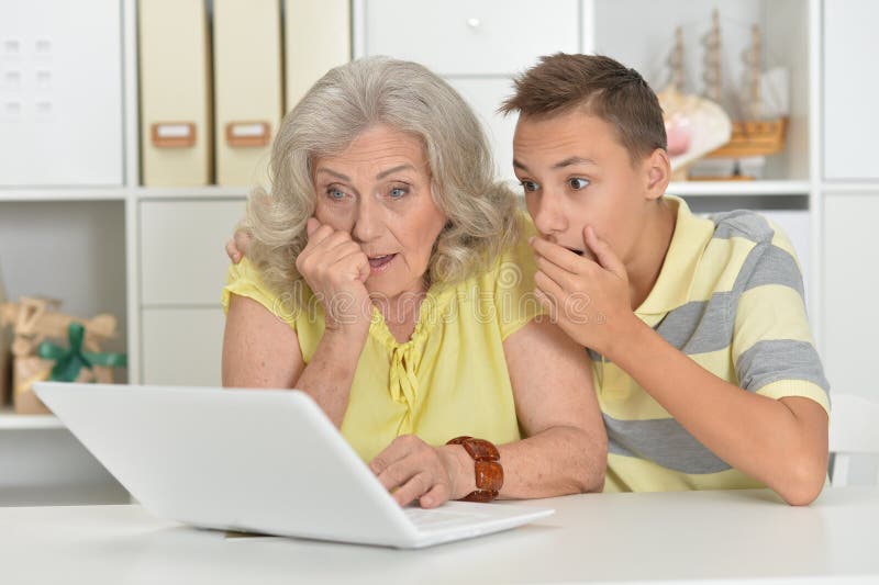 Oma met kleinzoon die thuis een laptop gebruikt