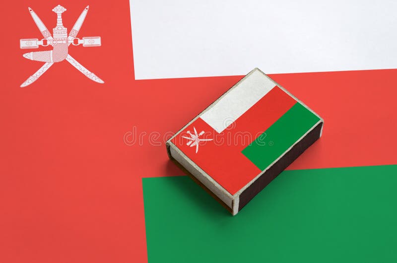 Oman flag is pictured on a matchbox that lies on a large flag royalty free stock photography
