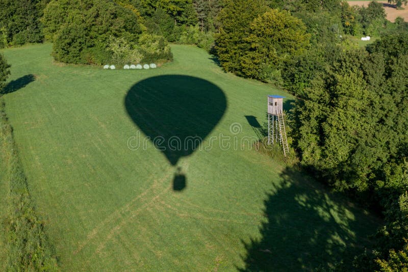 Ombra ad aria calda del balloonÅ sul campo verde con il pellame