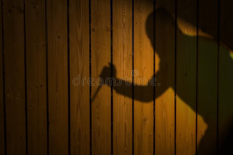 Shadow or silhouette of criminal with knife on fence at night. Shadow or silhouette of criminal with knife on fence at night.