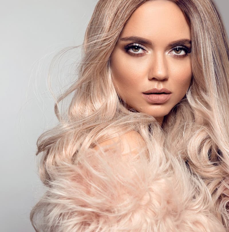 Ombre blond hairstyle. Beauty fashion blonde portrait. Sexy woman wears in pink fur coat. Beautiful girl model with makeup, long healthy hair style posing isolated on studio grey background