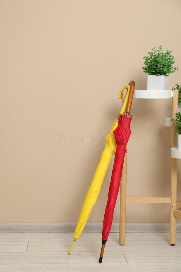 Ombrelli colorati e casalinghe vicino a un muro beige, spazio per testo fotografia stock libera da diritti