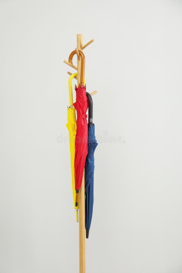 Ombrelli colorati su un rack di indumenti con fondo grigio chiaro immagine stock