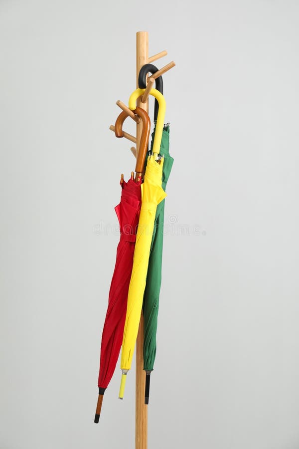 Ombrelli colorati su un rack di indumenti con fondo grigio chiaro fotografia stock libera da diritti