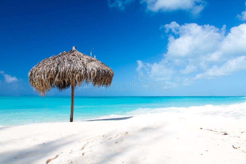 Ombrello di spiaggia su una spiaggia bianca perfetta davanti al mare. Ombrello di spiaggia fatto delle foglii di palma su una spiaggia bianca perfetta davanti al mare. Il giusto posto per si rilassa e vacanze