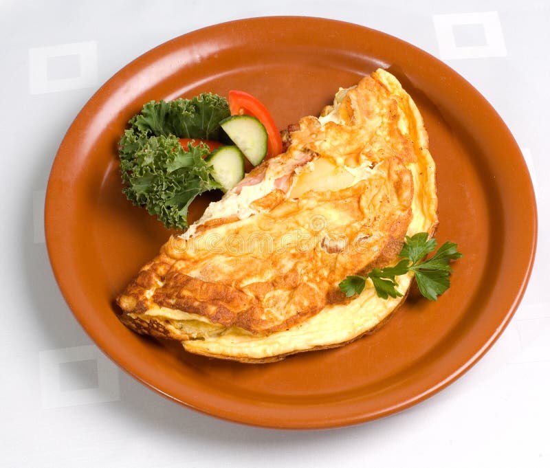 Šunka a sýr omeleta na hnědé desky s bylinkové a zeleninové ozdoby.