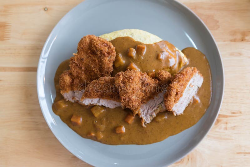 Omelette Rice with Japanese Curry and Breaded Deep Fried Pork Cutlet on Modern Wood Table stock photography Omelette Rice with Japanese Curry and Breaded Deep Fried Pork Cutlet on Modern Wood Table stock photography