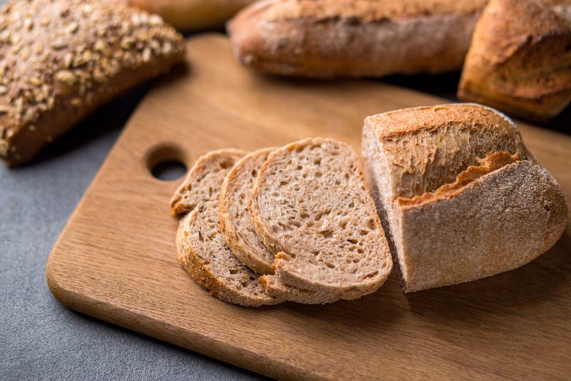 Omhoog sluit het vers gebakken gesneden brood op houten scherpe raad op de grijze steenlijst, stock fotografie Omhoog sluit het vers gebakken gesneden brood op houten scherpe raad op de grijze steenlijst, stock fotografie