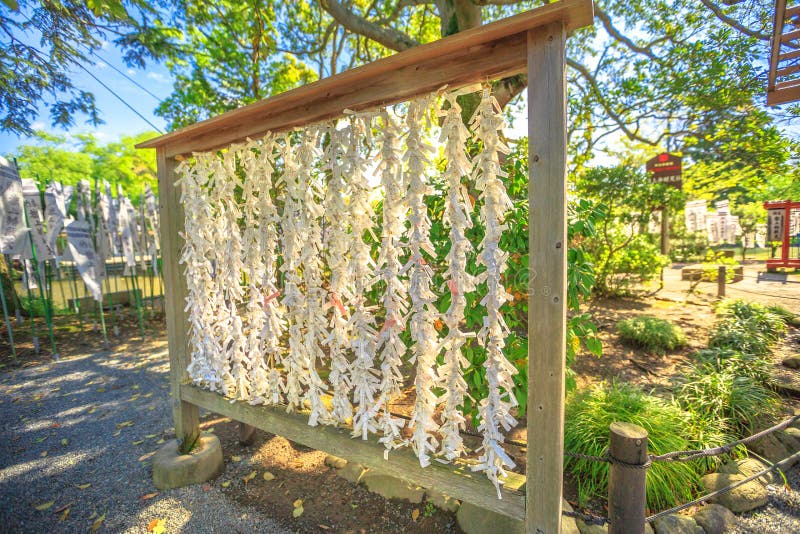 Kamakura, Japan - April 23, 2017: a lot of Omikuji tied to ropes at Tsurugaoka Hachiman. O-mikuji are random fortunes written on strips of paper at Shinto shrines and Buddhist temples in Japan. Kamakura, Japan - April 23, 2017: a lot of Omikuji tied to ropes at Tsurugaoka Hachiman. O-mikuji are random fortunes written on strips of paper at Shinto shrines and Buddhist temples in Japan